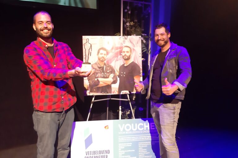 Twee mannen poseren met award bij evenement.