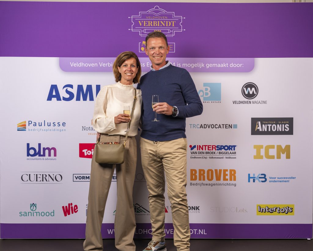 Koppel poseert bij Veldhoven Verbindt 2024 sponsorwand.