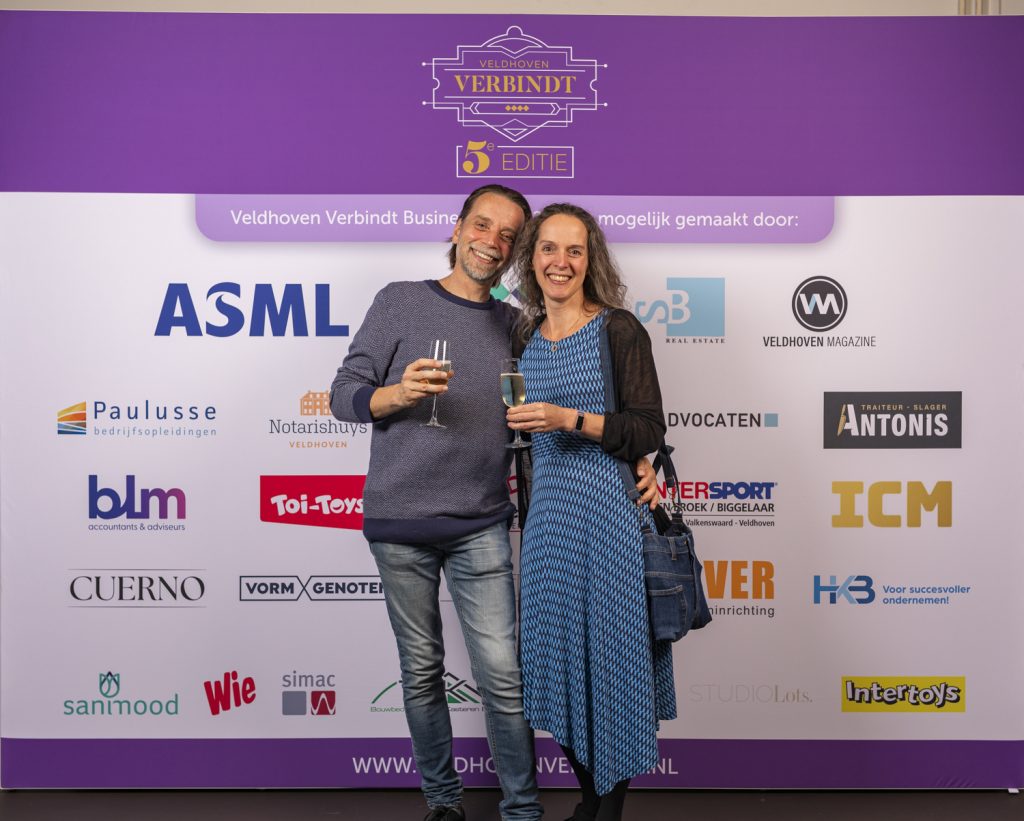 Twee mensen poseren voor Veldhoven Verbindt banner.