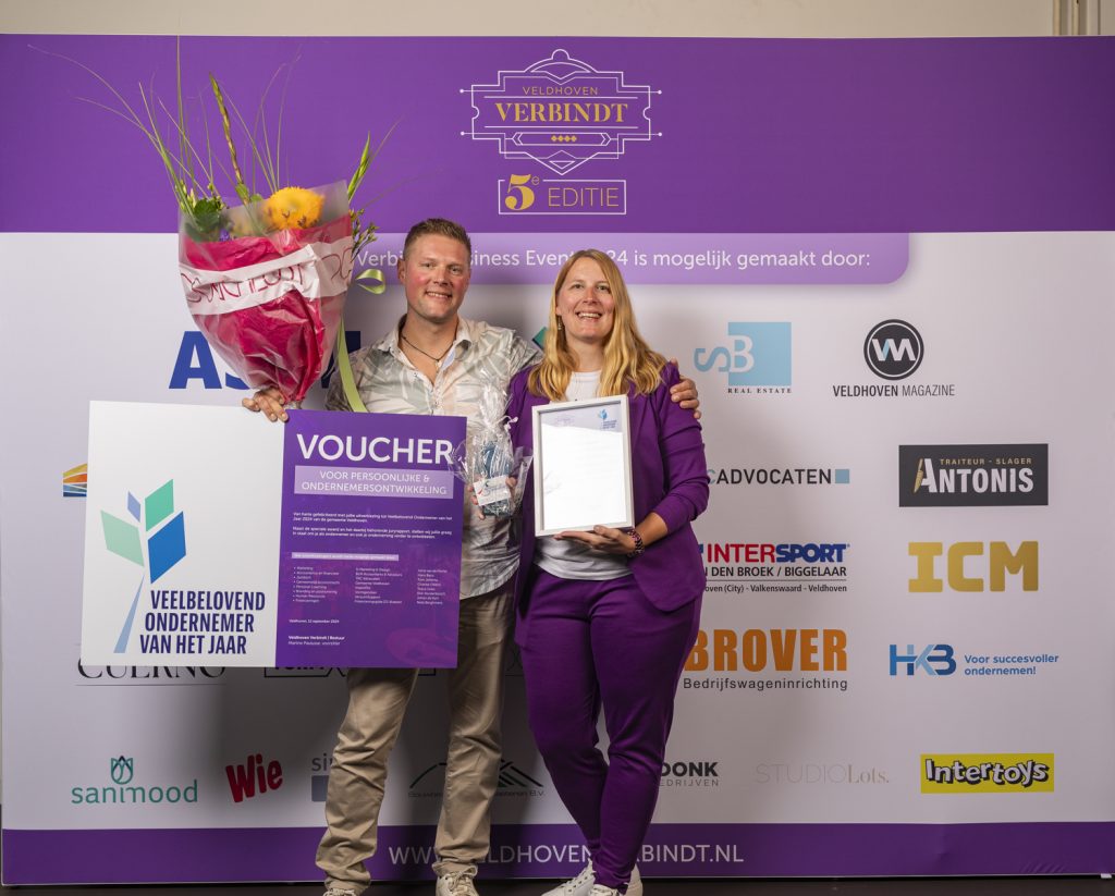 Twee mensen bij Veldhoven Verbindt evenement met bloemen, voucher.