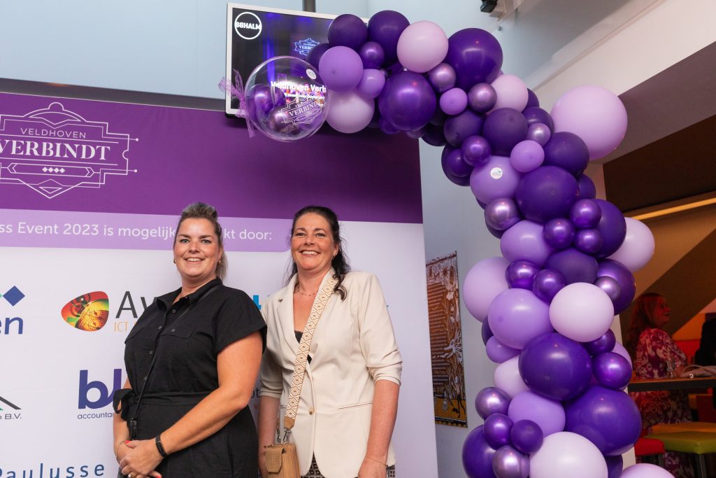 Twee vrouwen bij paarse ballonboog op Veldhoven Verbindt event.