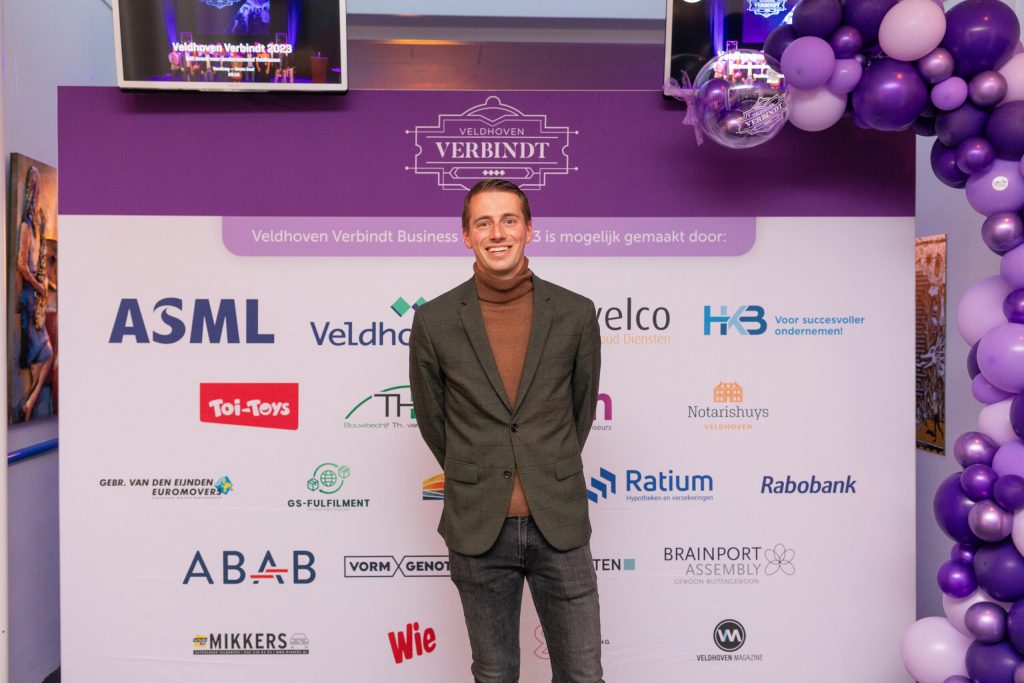 Man staat voor Veldhoven Verbindt banner met logo's.