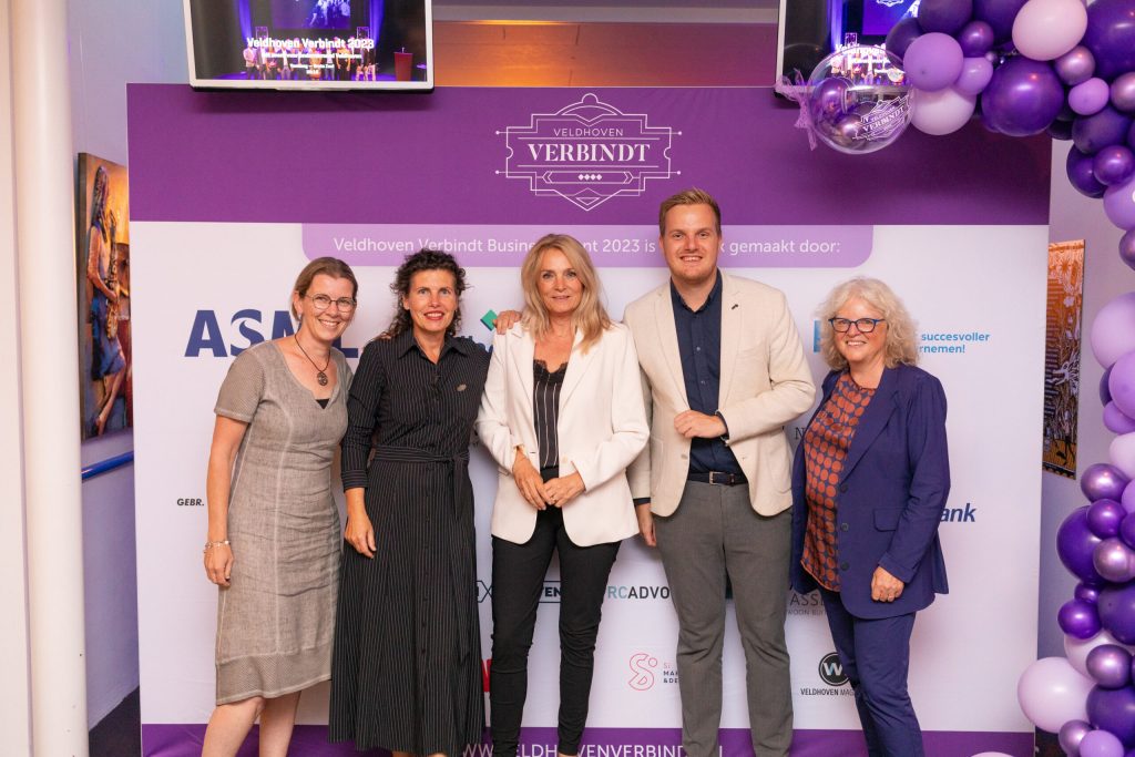Groepsfoto bij Veldhoven Verbindt evenement, paarse achtergrond.