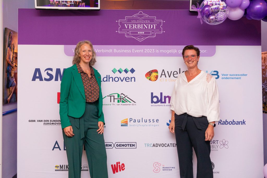 Twee vrouwen voor Veldhoven Verbindt banner met logo's.