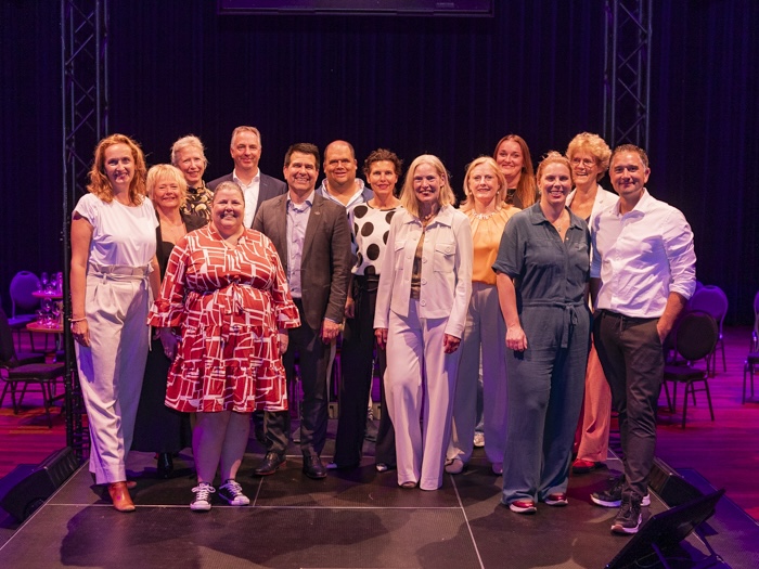 Groep mensen poseert samen op een podium.